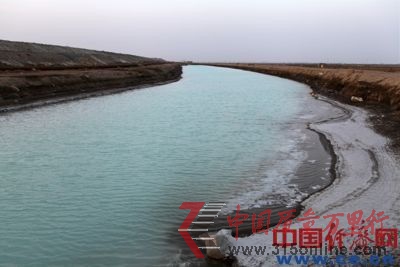 河溝中滿是藍綠色的堿性污水，河邊結(jié)出了厚厚一層堿。
